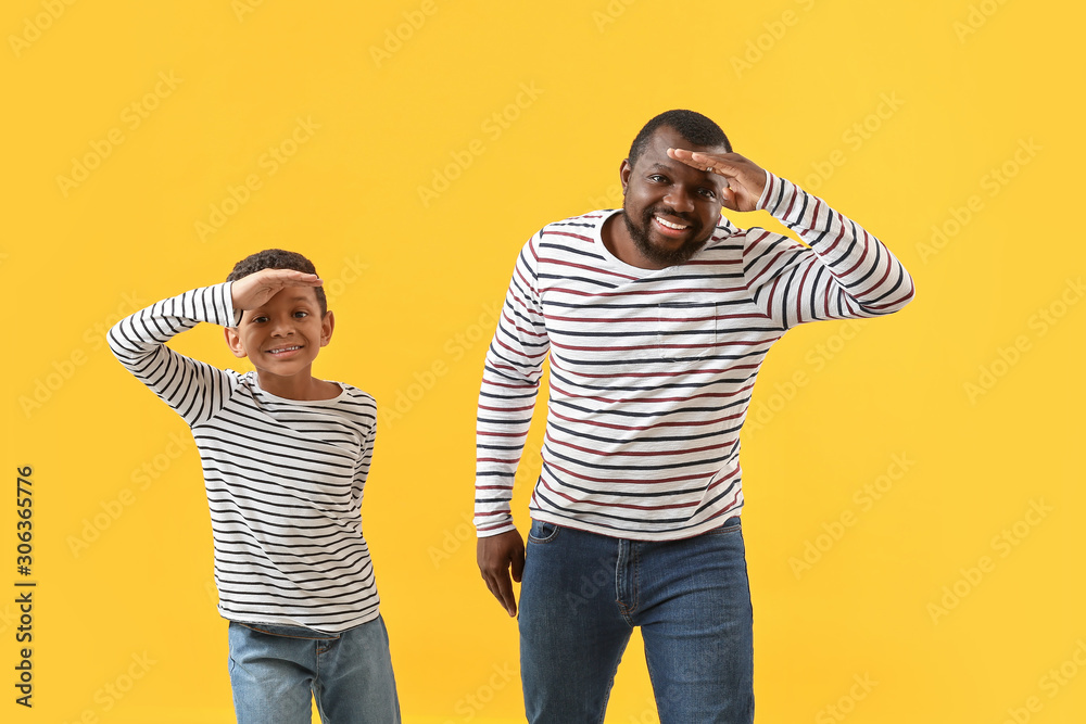 Portrait of African-American man with his little son on color background