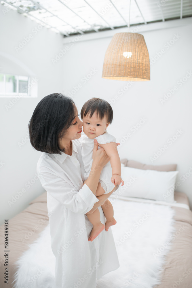 Young mother playing with her little girl at the bedroom