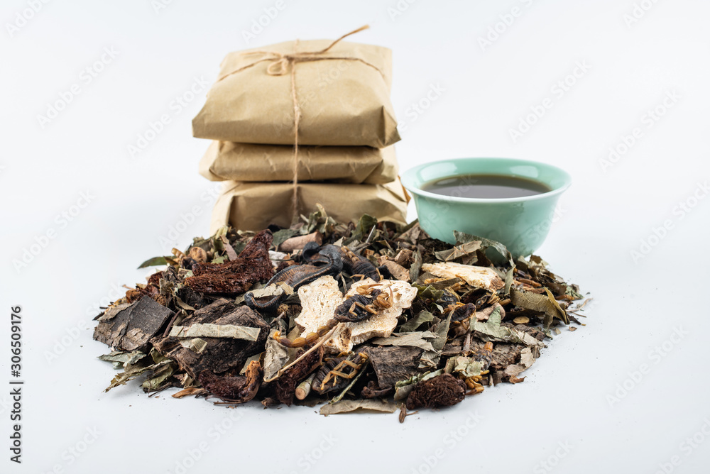 A pile of Chinese medicinal herbs and cooked soup on white background