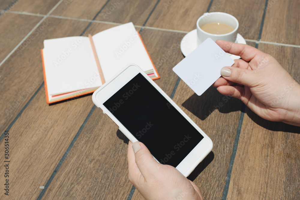 Close up woman hand holding credit card and blank screen mobile phone sitting at coffee shop