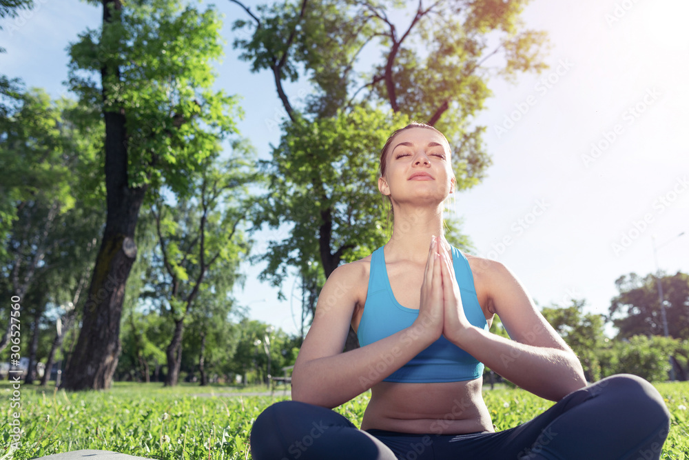 Girl meditates in lotus pose on green grass