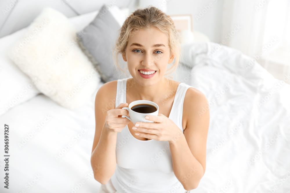 Morning of beautiful young woman drinking coffee in bedroom