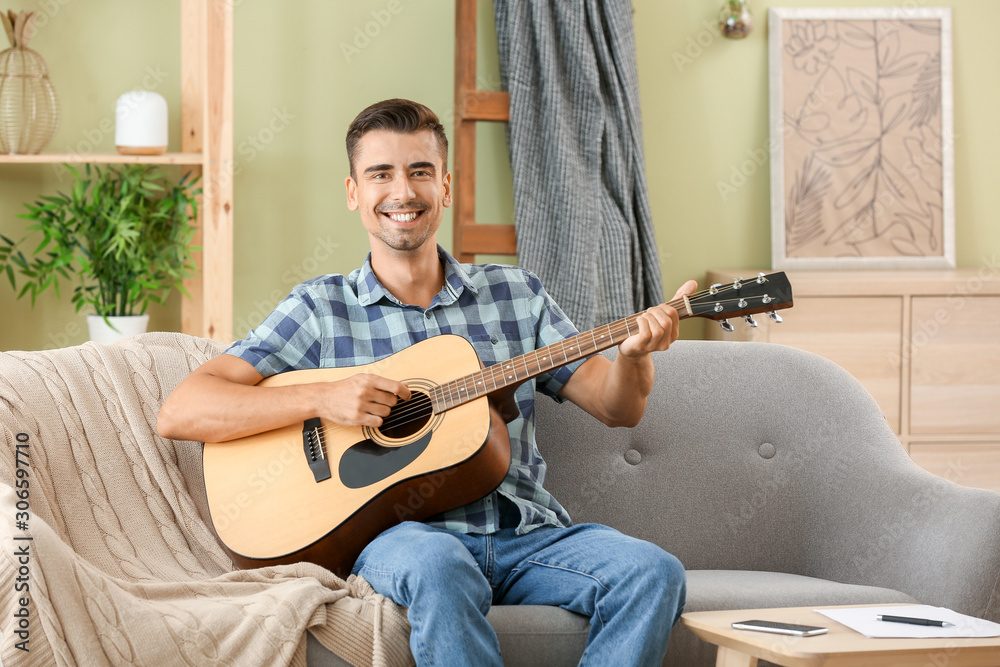 Handsome man playing guitar at home