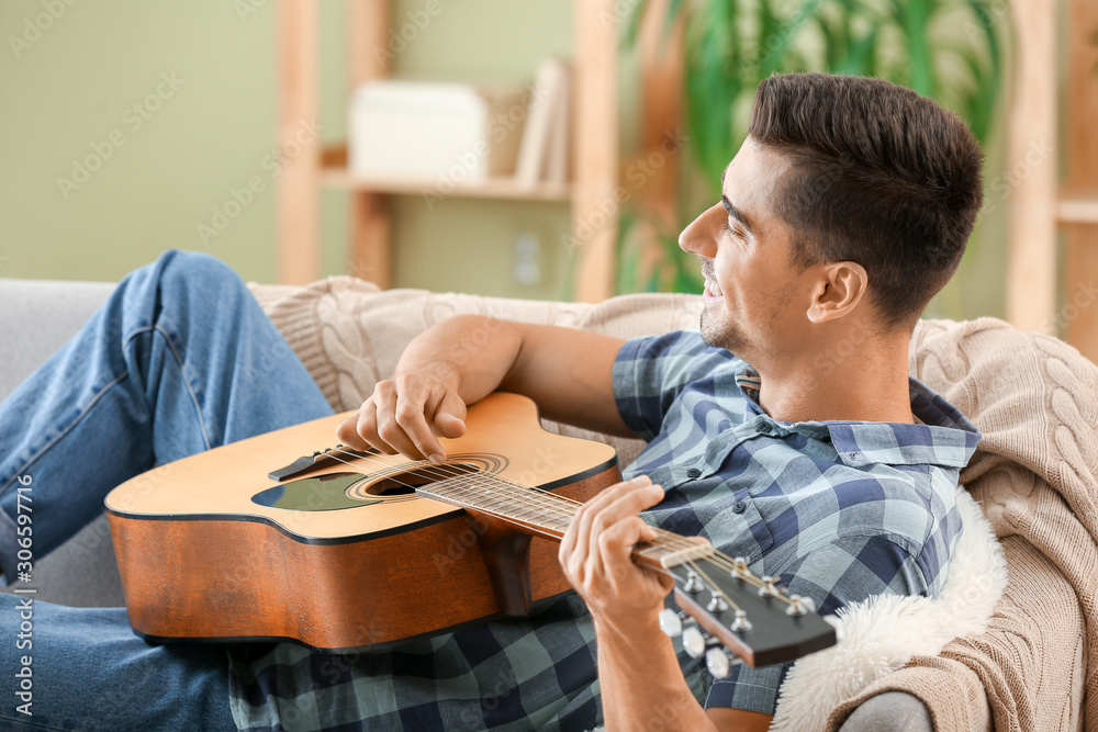 Handsome man playing guitar at home