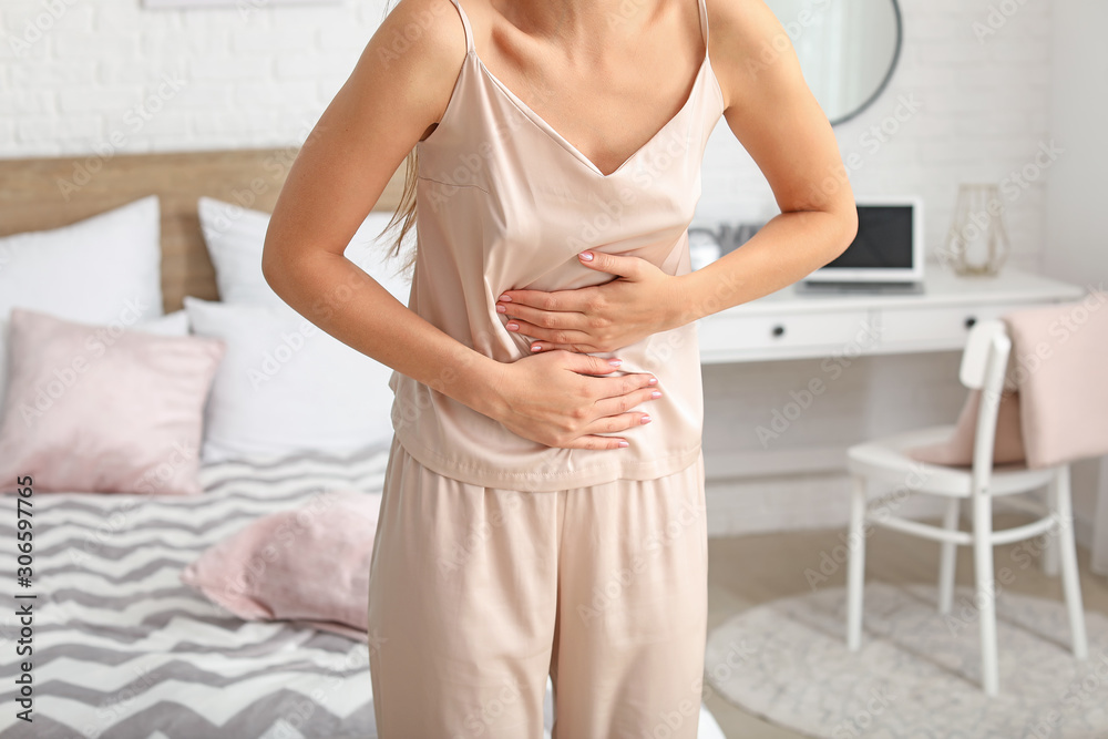 Young woman suffering from abdominal pain at home