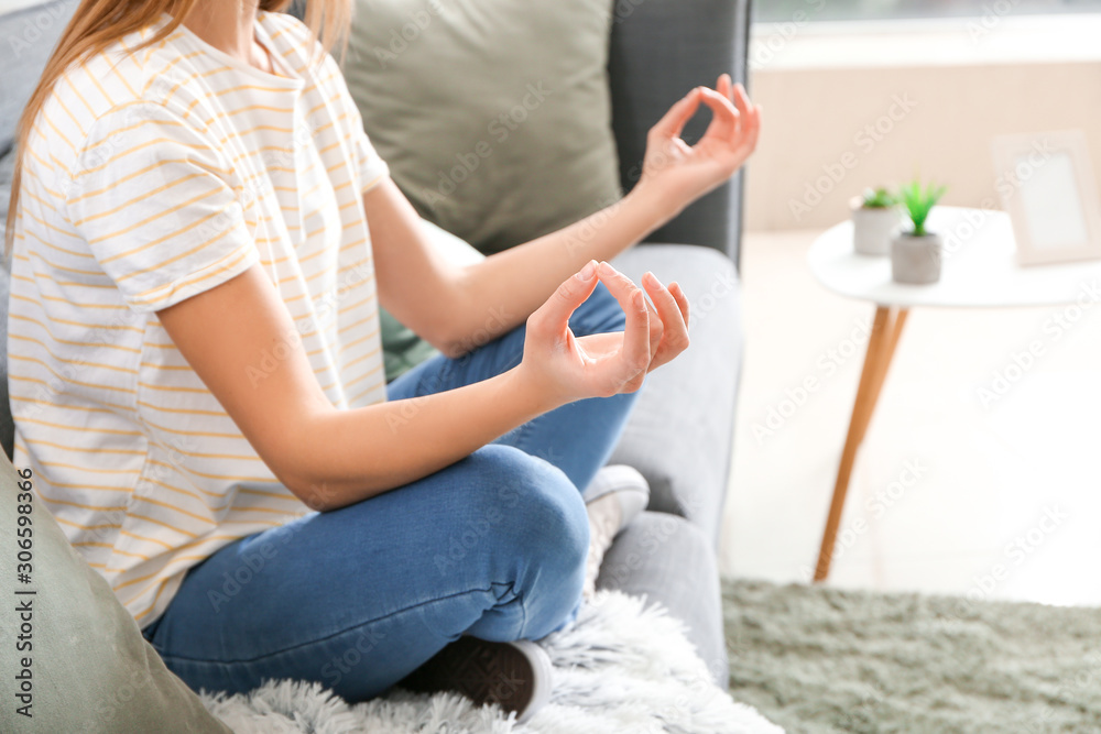 Beautiful young woman meditating at home