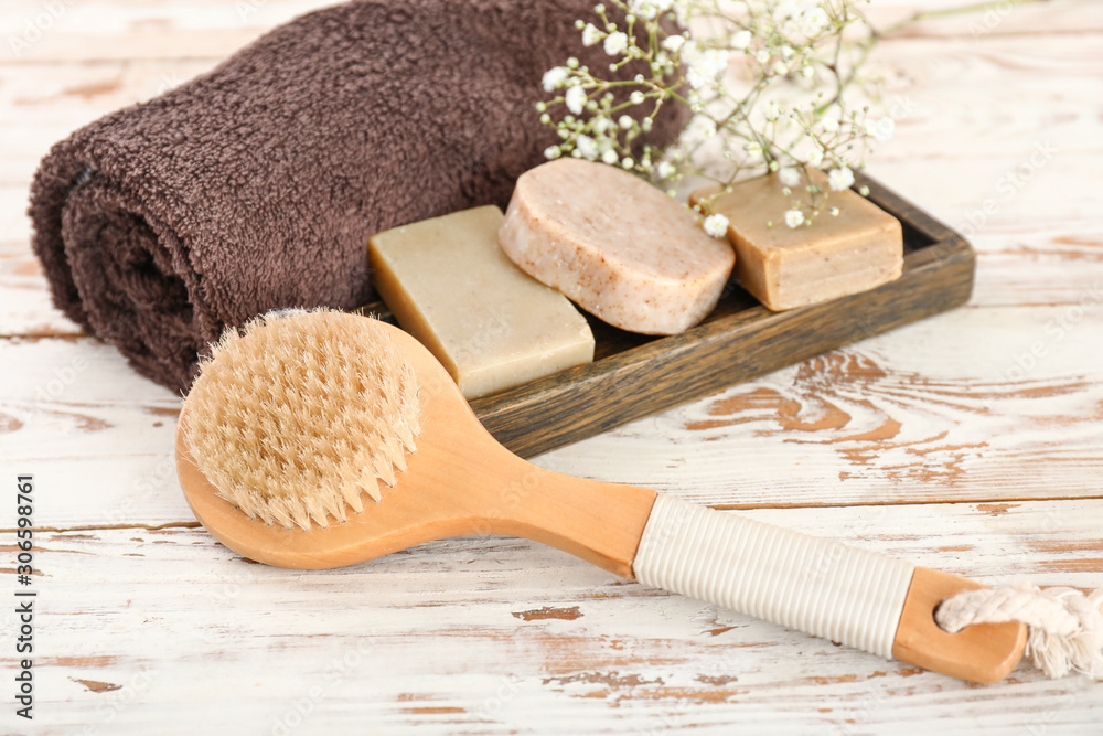 Brush, soap and towel on wooden background