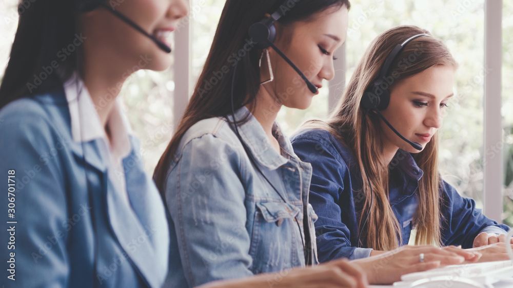 Customer support agent or call center with headset works on desktop computer while supporting the cu