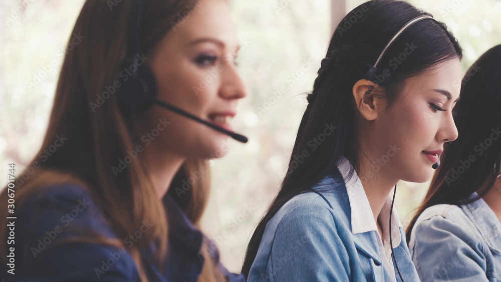 Customer support agent or call center with headset works on desktop computer while supporting the cu