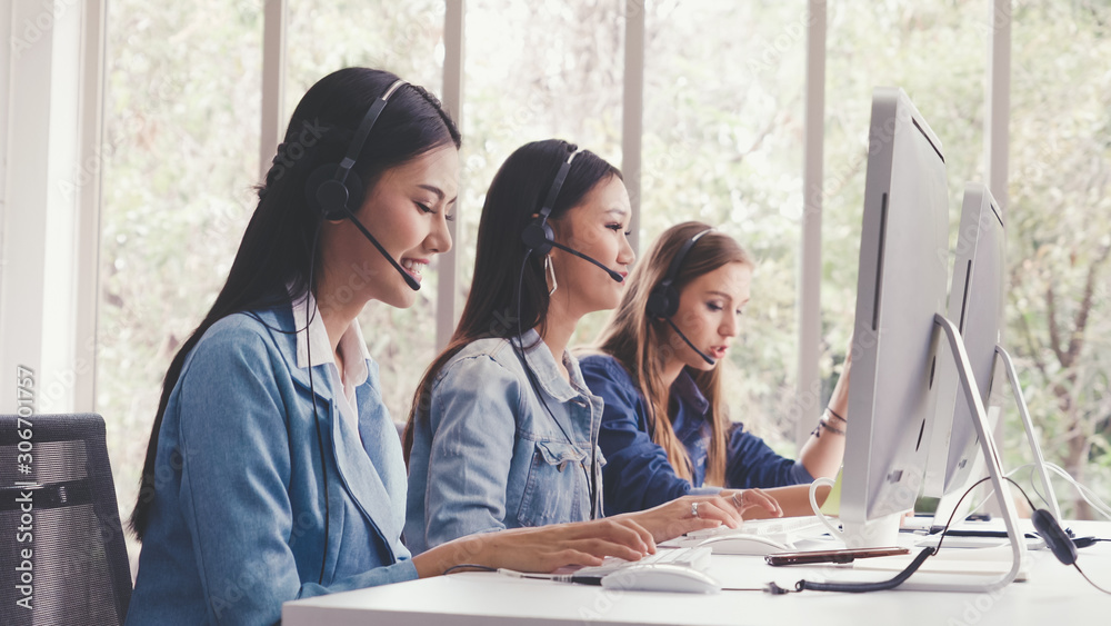 Customer support agent or call center with headset works on desktop computer while supporting the cu