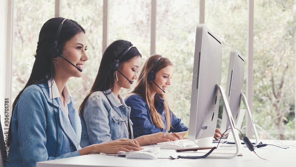 Customer support agent or call center with headset works on desktop computer while supporting the cu