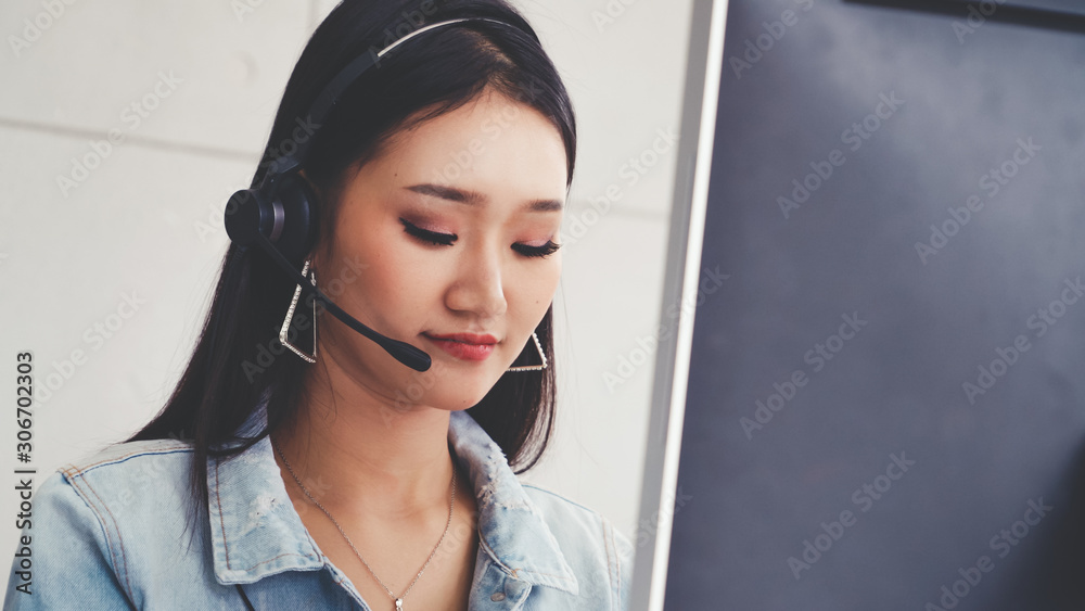 Customer support agent or call center with headset works on desktop computer while supporting the cu