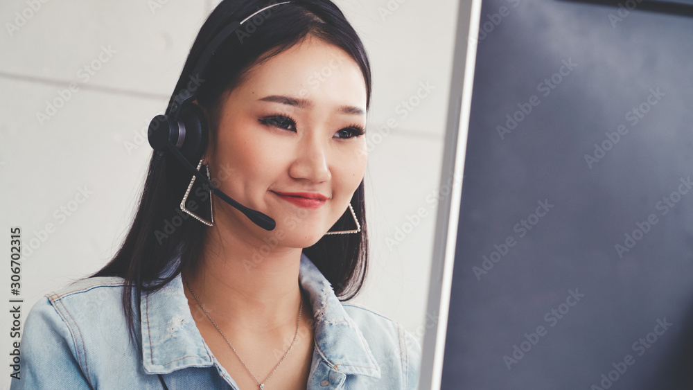 Customer support agent or call center with headset works on desktop computer while supporting the cu