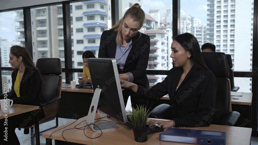 Young leader gives advice to young woman worker in modern office. Leadership and training concept.