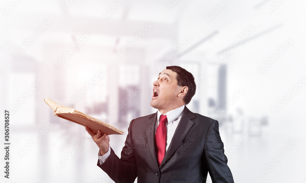 Surprised businessman holding open book