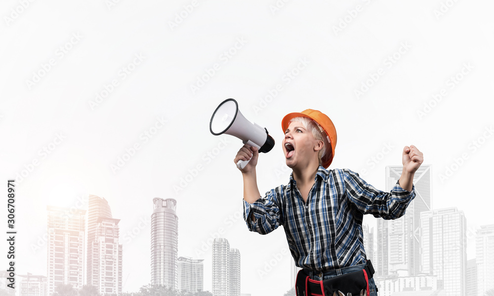 Expressive woman in helmet shouting into megaphone