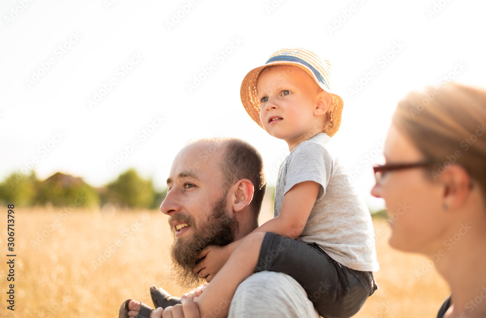 Happy family walking together with child on piggyback