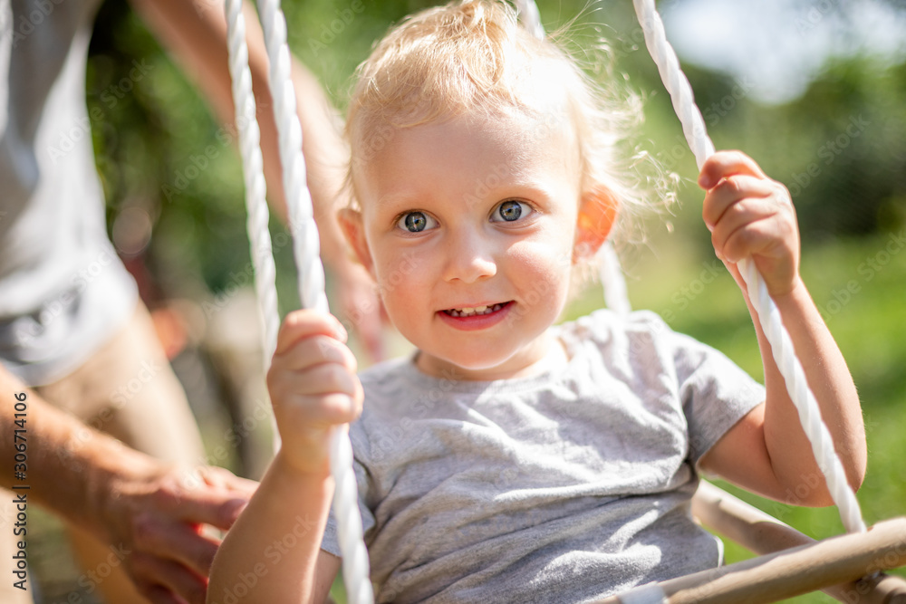 Happy father pushing laughing son on swing in backyard