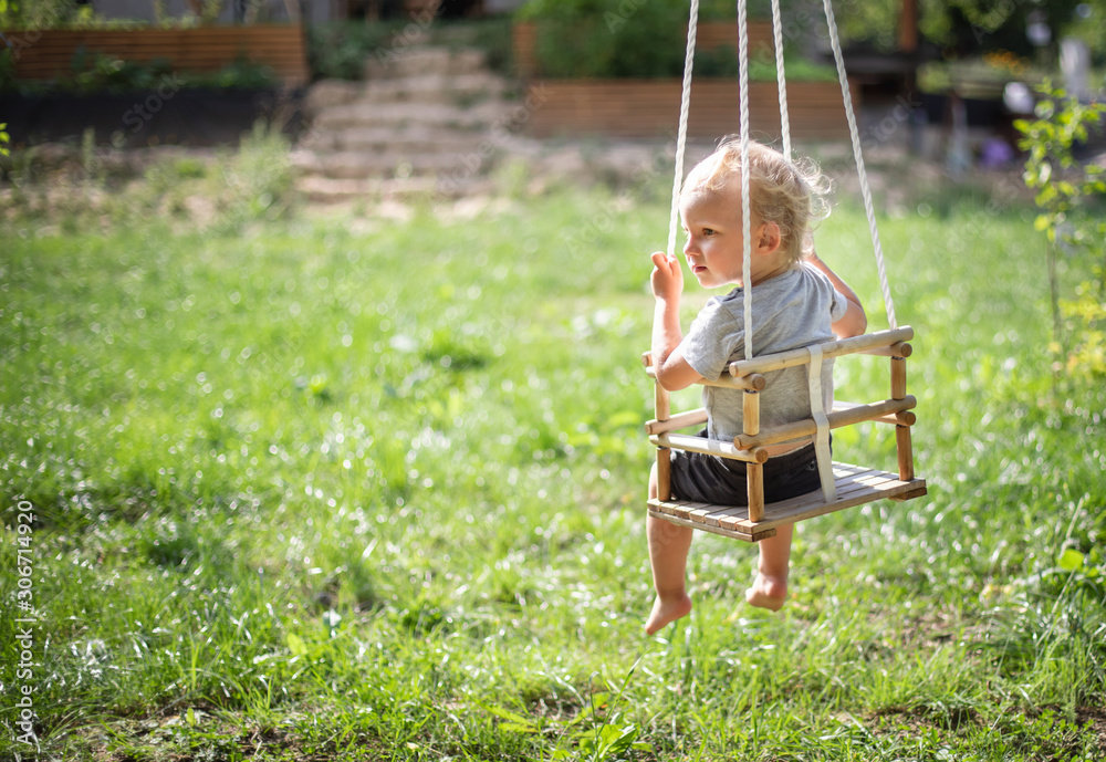 Little boy playing on swing in backyard at coutryside