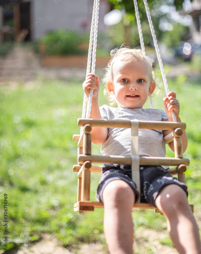 Little boy playing on swing in backyard at coutryside