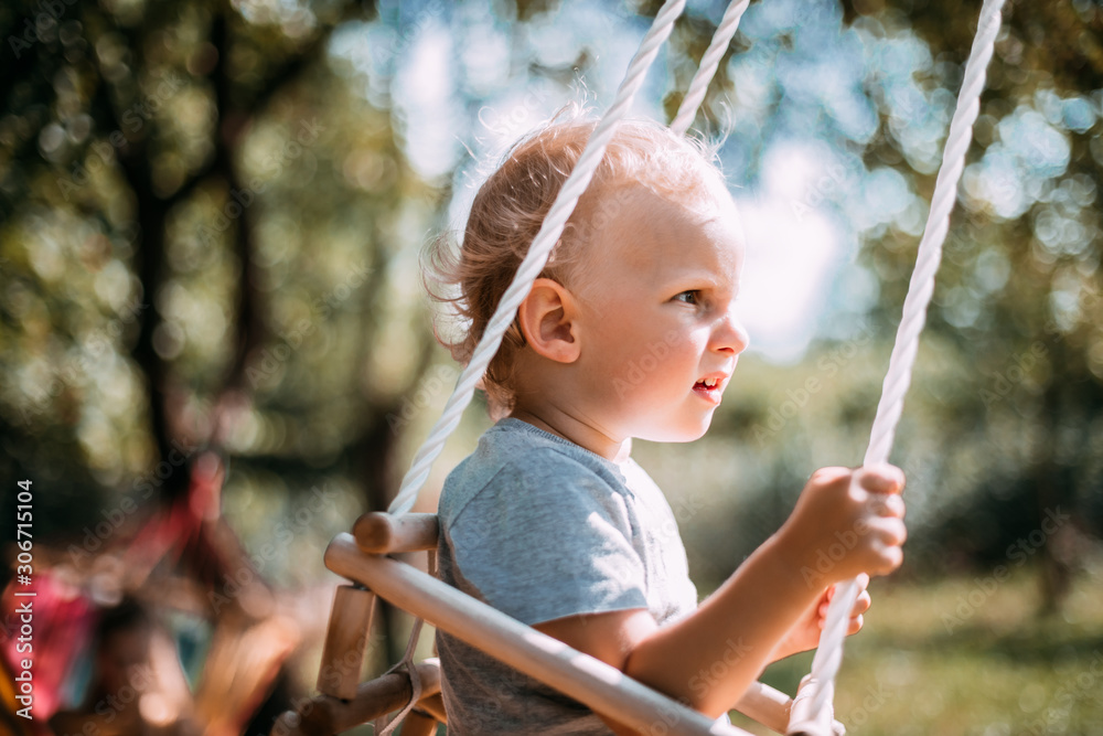 Little boy playing on swing in backyard at coutryside