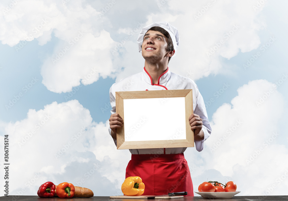 Young male chef standing near cooking table