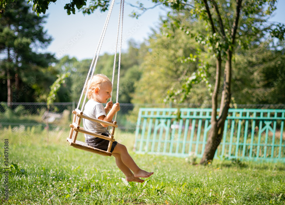 Little boy playing on swing in backyard at coutryside