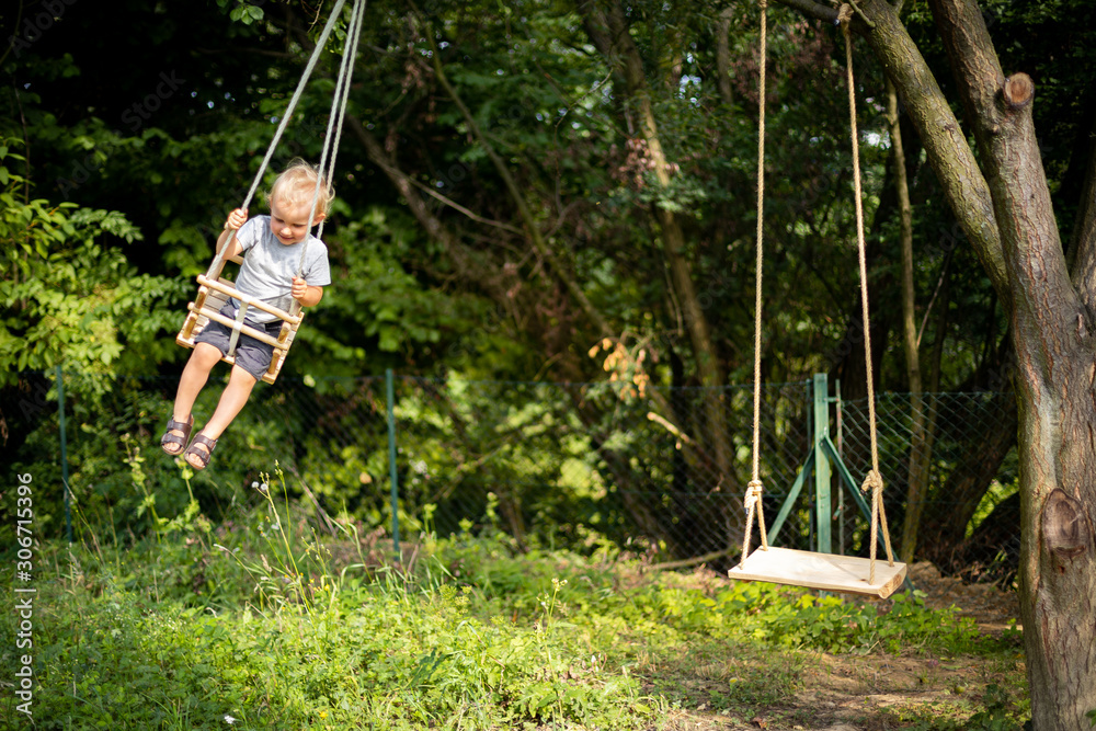 Little boy playing on swing in backyard at coutryside