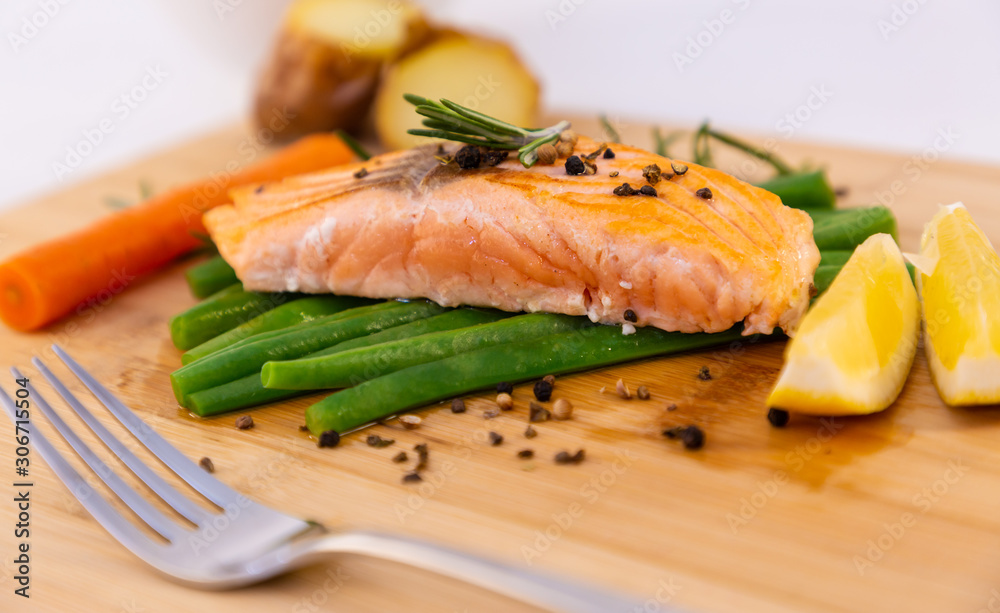 Grilled fresh salmon steak with roasted green beans, baked potatoes, lime and salad vegetables is a 