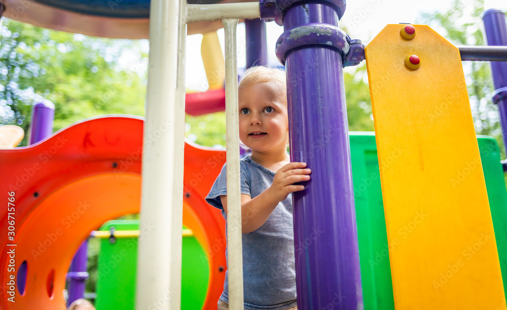 Little child boy playing on playground in the city park