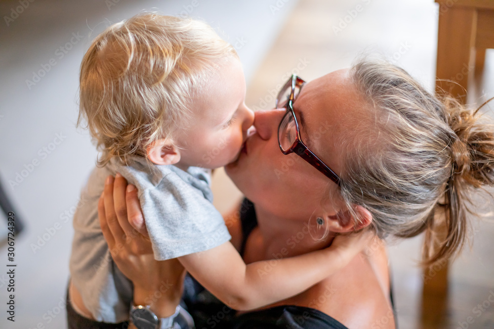 Young mom kissing his child son at home