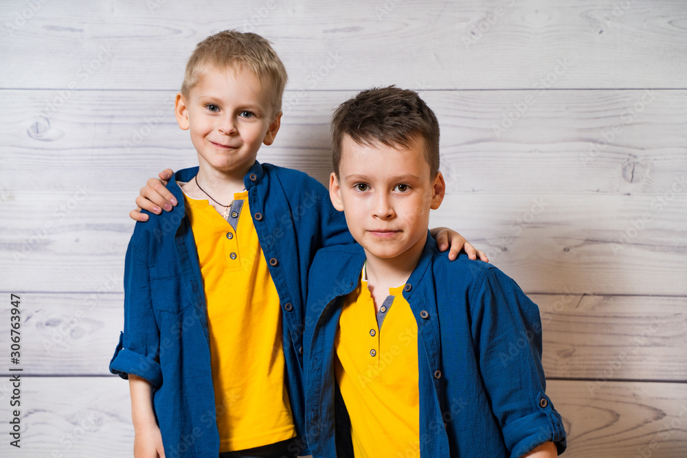 Emotional portraits of happy and positive little brothers, looking and smiling to the camera, huggin