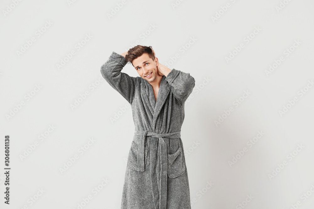 Handsome man in bathrobe on grey background