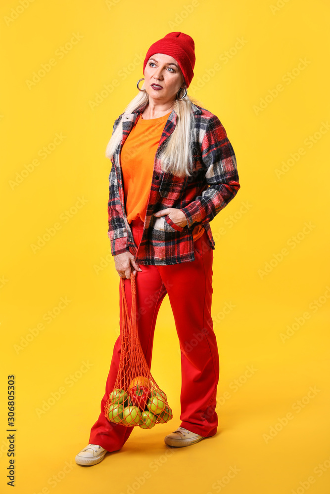 Fashionable mature woman on color background