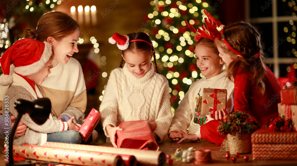 happy family mother and children pack Christmas gifts.