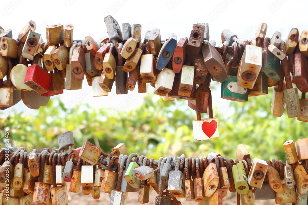 white key with red heart sticker and many old rust key lock with rust iron fence on blur background 