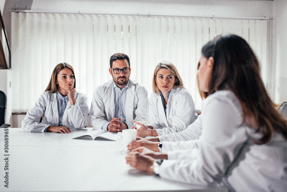 Serious medical team talking while sitting at the table.