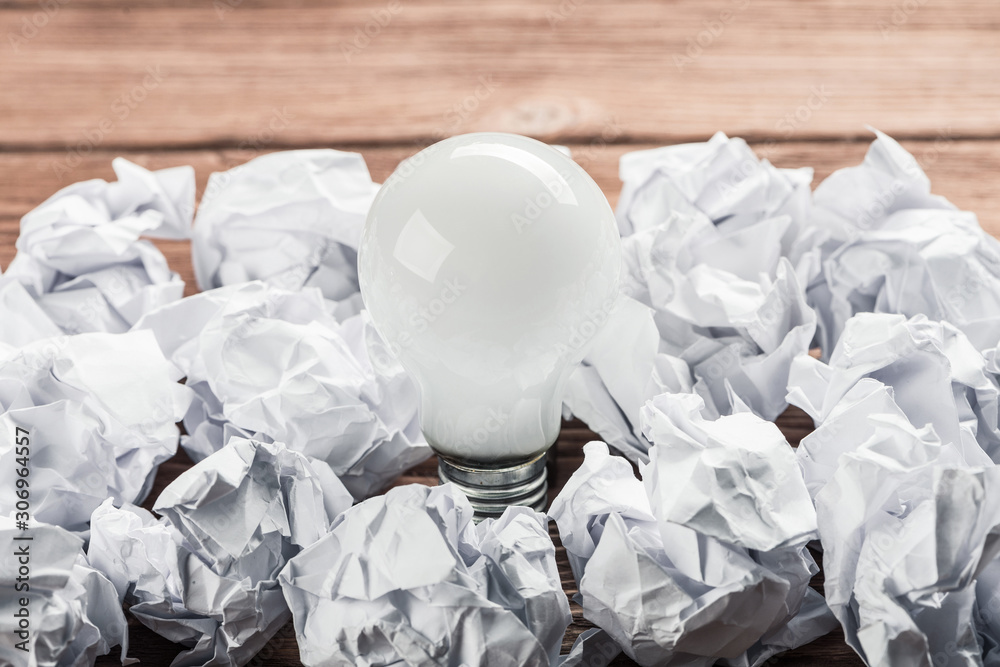 Ideological concept with wastepaper light bulb on wooden table