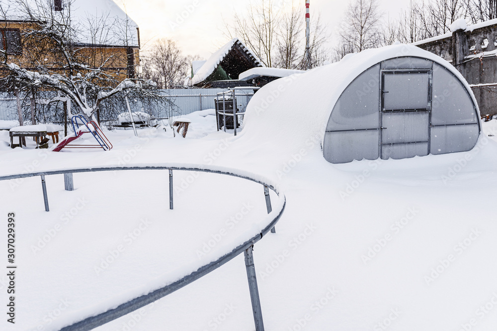 冬天，雪，花园里有霜。花园里有儿童覆盖的滑梯。白雪上有蹦床。