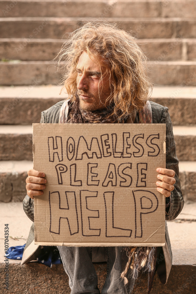 Portrait of poor homeless man sitting on stairs outdoors