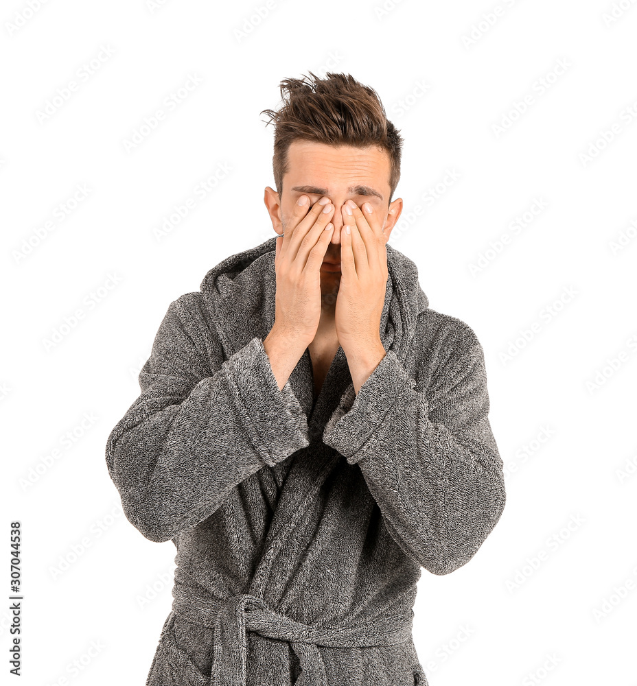 Sleepy man in bathrobe on white background