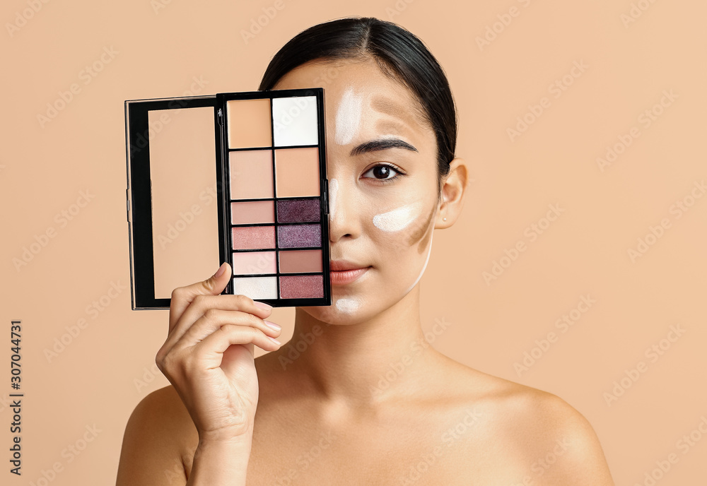 Young Asian woman with cosmetics for contouring makeup on color background