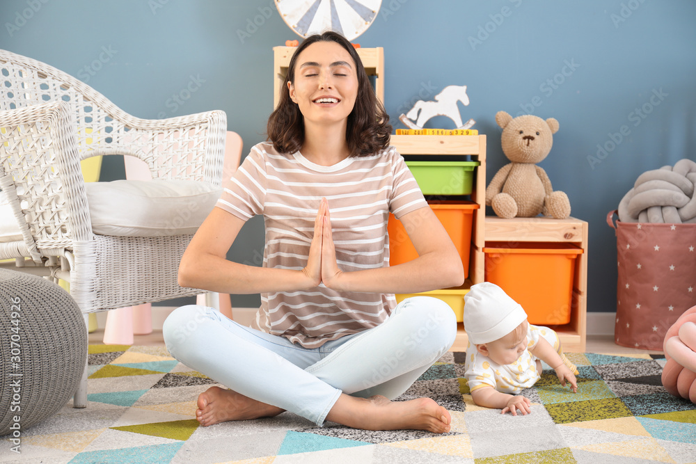 Young mother with little baby meditating at home