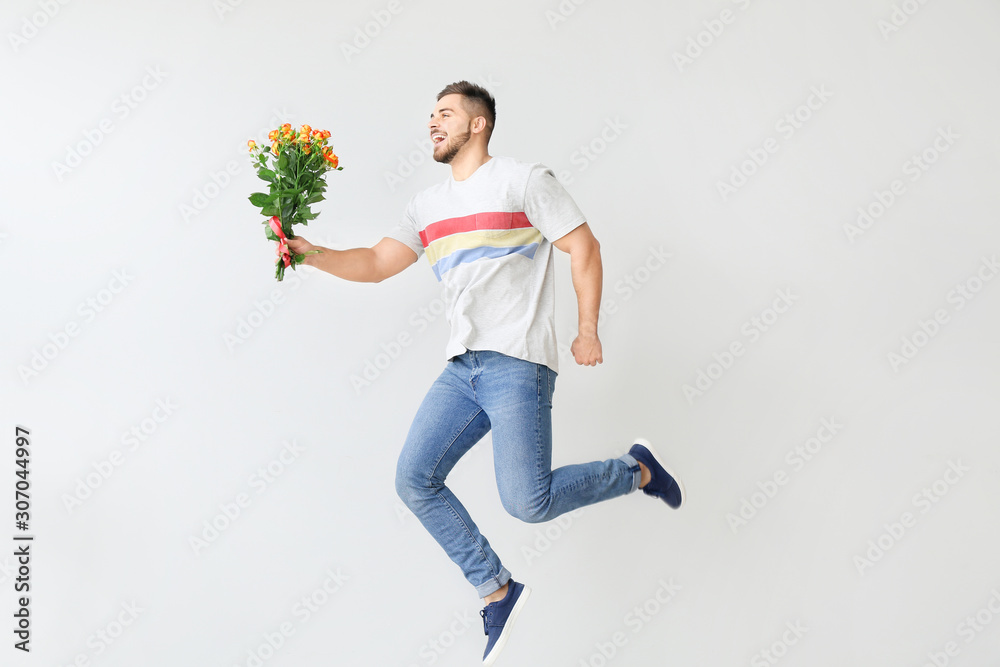 Handsome jumping man with flowers on light background. Valentines Day celebration