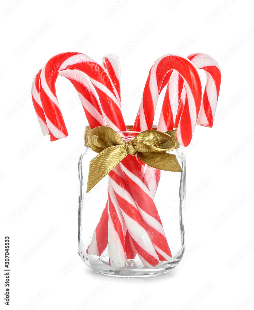 Glass jar with Christmas candy canes on white background