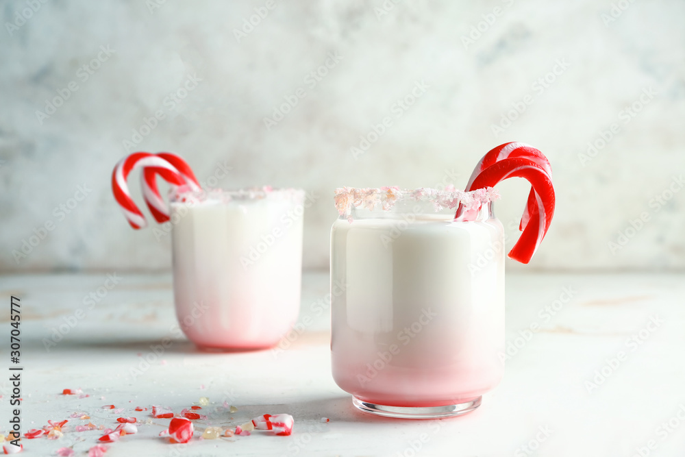 Glasses with tasty milk cocktail and Christmas candy canes on table