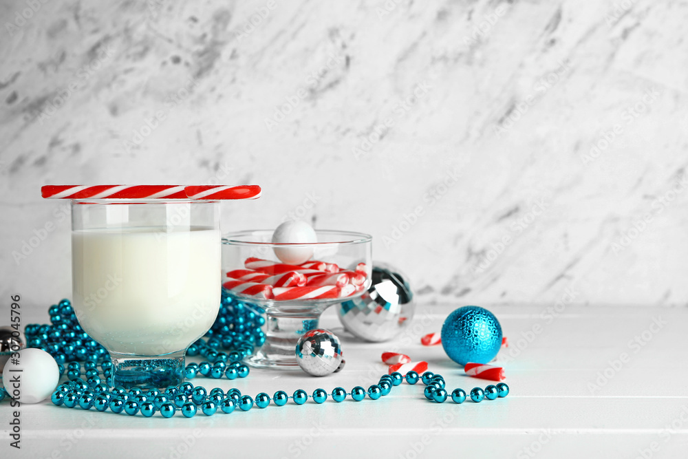 Glass of milk, Christmas candy canes and decor on table