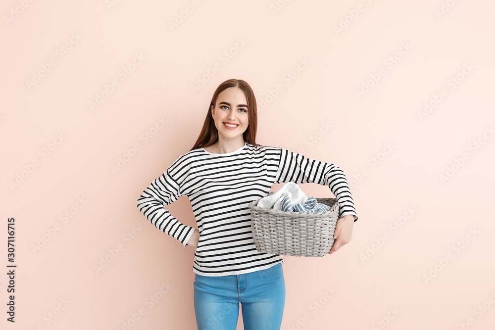 Beautiful young woman with laundry on color background