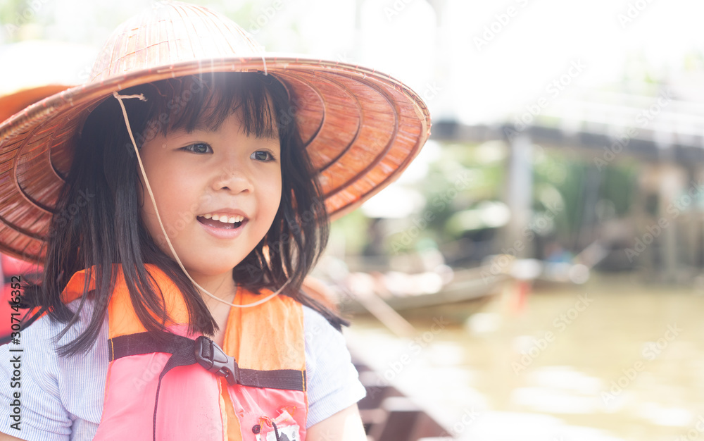 Little thai girl with thai natural local hat and life jacket.She smiling, exciting and laughing in l