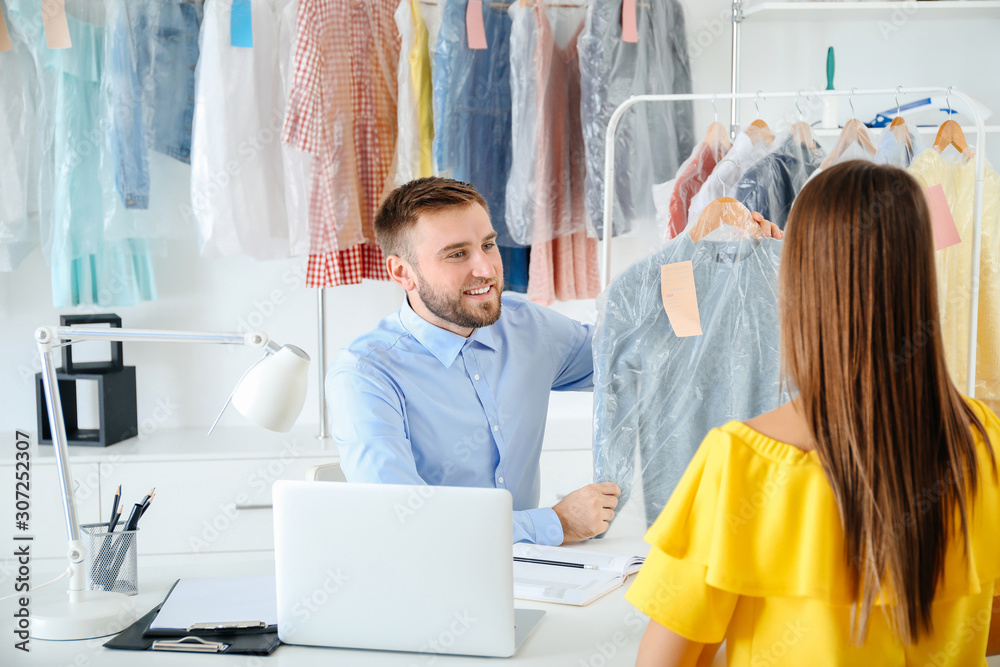 Client taking clothes from modern dry-cleaners